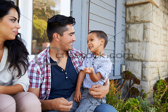 Parents With Son Sitting On Steps Outside Home