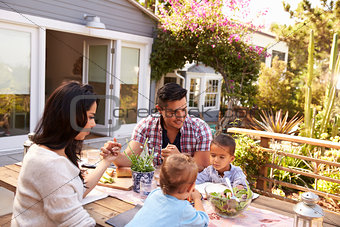 Family Saying Grace Before Outdoor Meal In Garden