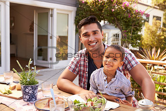 Father And Son Eating Outdoor Meal In Garden Together