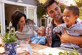 Family At Home Eating Outdoor Meal In Garden Together