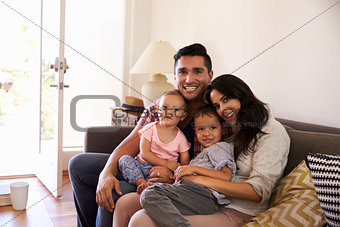 Portrait Of Happy Family Sitting On Sofa In at Home