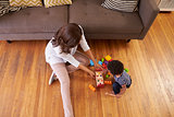 Mother And Son Playing With Toys On Floor At Home