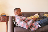 Man Relaxing On Sofa At Home Using Laptop