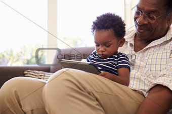 Grandfather And Grandson At Home Using Digital Tablet
