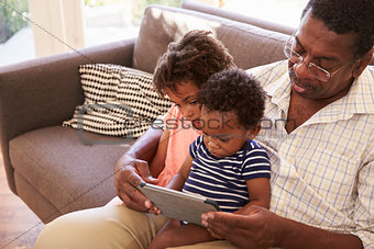 Grandfather And Grandchildren At Home Using Digital Tablet