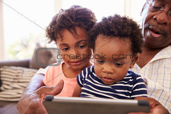 Grandfather And Grandchildren At Home Using Digital Tablet