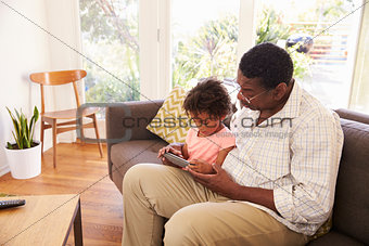 Grandfather And Granddaughter At Home Using Digital Tablet