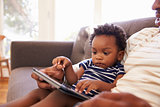 Father And Son Sitting On Sofa At Home Using Digital Tablet