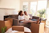 Couple On Sofa Taking A Break From Unpacking On Moving Day