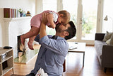 Father Sits At Table And Plays With Baby Son At Home