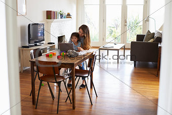 Mother And Daughter Using Laptop At Home Together