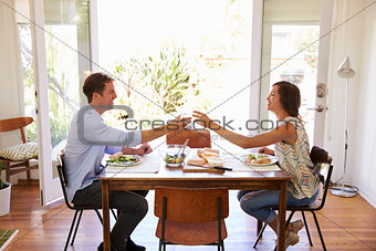 Couple Make A Toast As They Enjoy Meal At Home Together