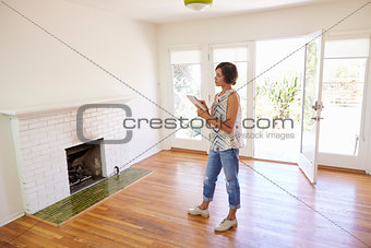 Female Realtor With Digital Tablet Looking Around House