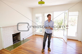 Male Realtor With Digital Tablet Looking Around House