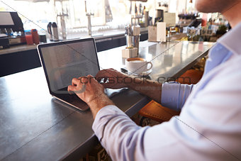Close Up Of Man Using Laptop In Coffee Shop