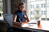 Businesswoman Working On Laptop And Making Notes On Document
