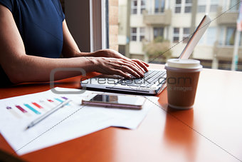 Close Up Of Businesswoman Sitting By Window Using On Laptop