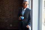 Mature Businessman Standing By Office Window With Coffee