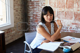 Businesswoman Making Notes On Document In Boardroom
