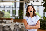 Laughing mixed race young businesswoman with arms crossed
