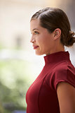 Young white businesswoman in maroon dress, side view, vertical