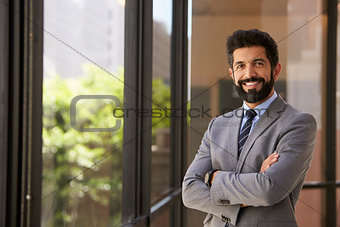 Smiling Hispanic businessman with arms crossed, to camera