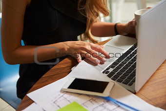 Businesswoman working in office using laptop, mid section