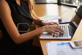 Businesswoman using laptop in office, mid section, side view