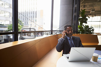 Middle aged black businessman using phone in a modern office