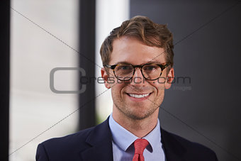 Young white businessman wearing glasses smiling, close up