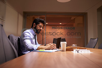 Middle aged Hispanic businessman working late in an office