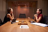 Two businesswomen working late sitting opposite each other