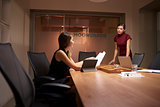 Businesswoman stands talking to colleague working late