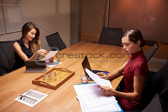 Two businesswomen doing paperwork late in an office