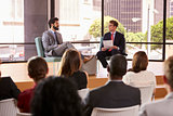 Speaker and interviewer in front of audience at a seminar