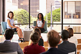 Two female speakers sit facing audience at business seminar
