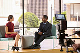Black man and white woman on set filming a TV interview
