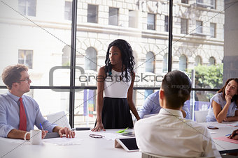 Young black businesswoman stands with colleagues at meeting