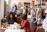 Two women talking at a table in a clothes design studio