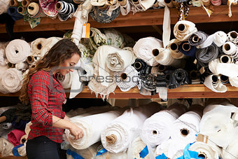 Young white woman selects fabric at a clothing design studio