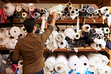Man reaching to select fabric from storage shelves