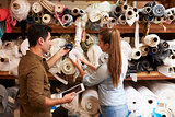Man and woman selecting fabric from storage shelves