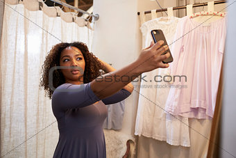 Woman taking selfie in a boutique changing room