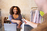 Assistant at clothes shop taking credit card from customer