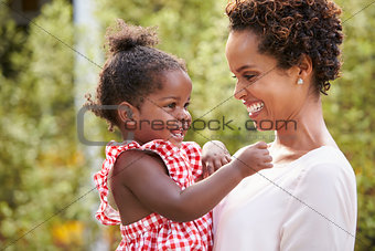 Young African American mother holds baby daughter in garden