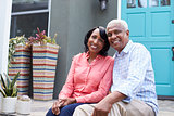 Senior couple sit on steps outside their house, close up