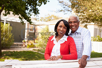 Senior black couple look to camera outside their new house