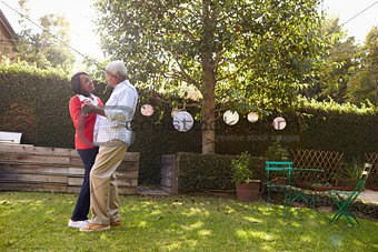 Senior black couple dance in their back garden, full length