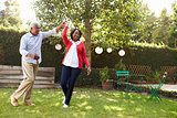 Senior black couple dance in their back garden, full length