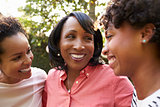 Black mother and two adult daughters in garden, close up